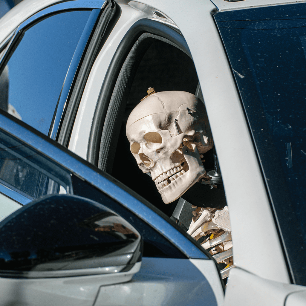 Un squelette d’Halloween assis sur le siège passager d’une voiture